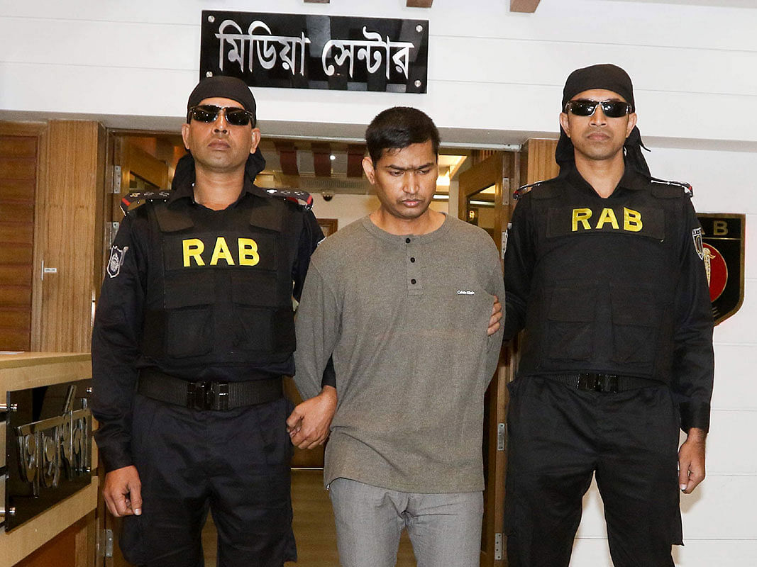 The Rapid Action Battalion (RAB) escort arrested suspected militant Mamunur Rashid (C) in Dhaka on 20 January, 2019. Photo: AFP