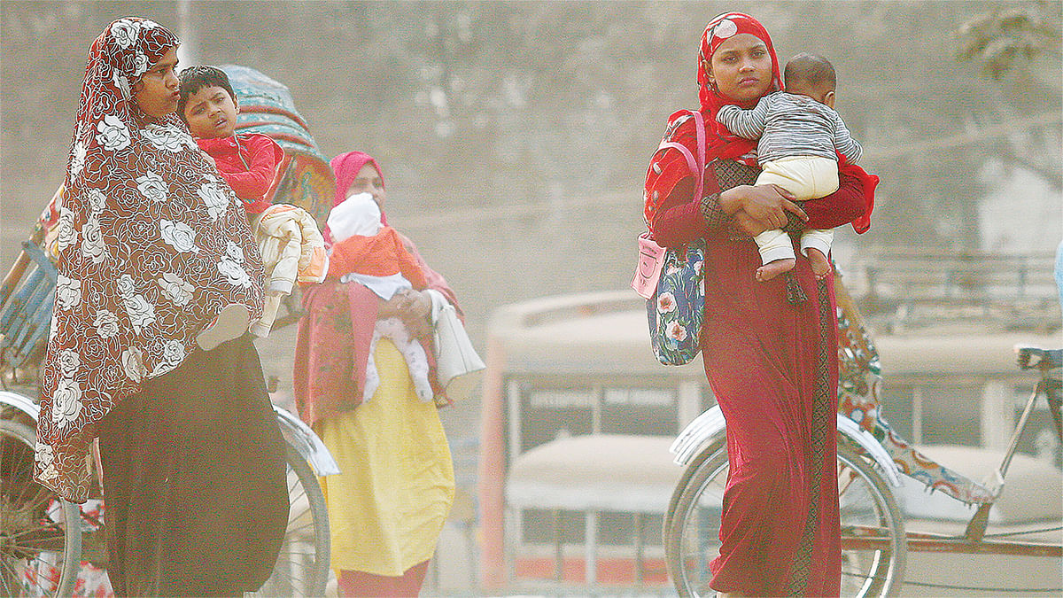 Women carrying children cross crossing a road in a cloud of dust at Postogola, Dhaka. Photo: Hasan Raja