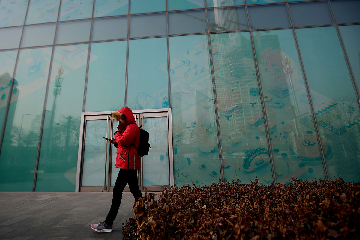 In this 12 January 2019, photo, a man walks by a vacant retail space window panels at the Central Business District in Beijing