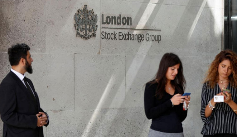 People check their mobile phones as they stand outside the entrance of the London Stock Exchange in London, Britain. on 23 August 2018. -- Photo: Reuters