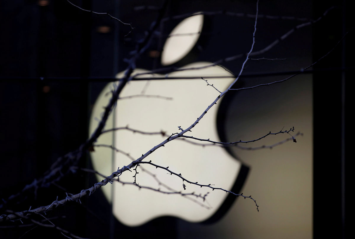 An Apple company logo is seen behind tree branches outside an Apple store in Beijing, China 14 December 2018.