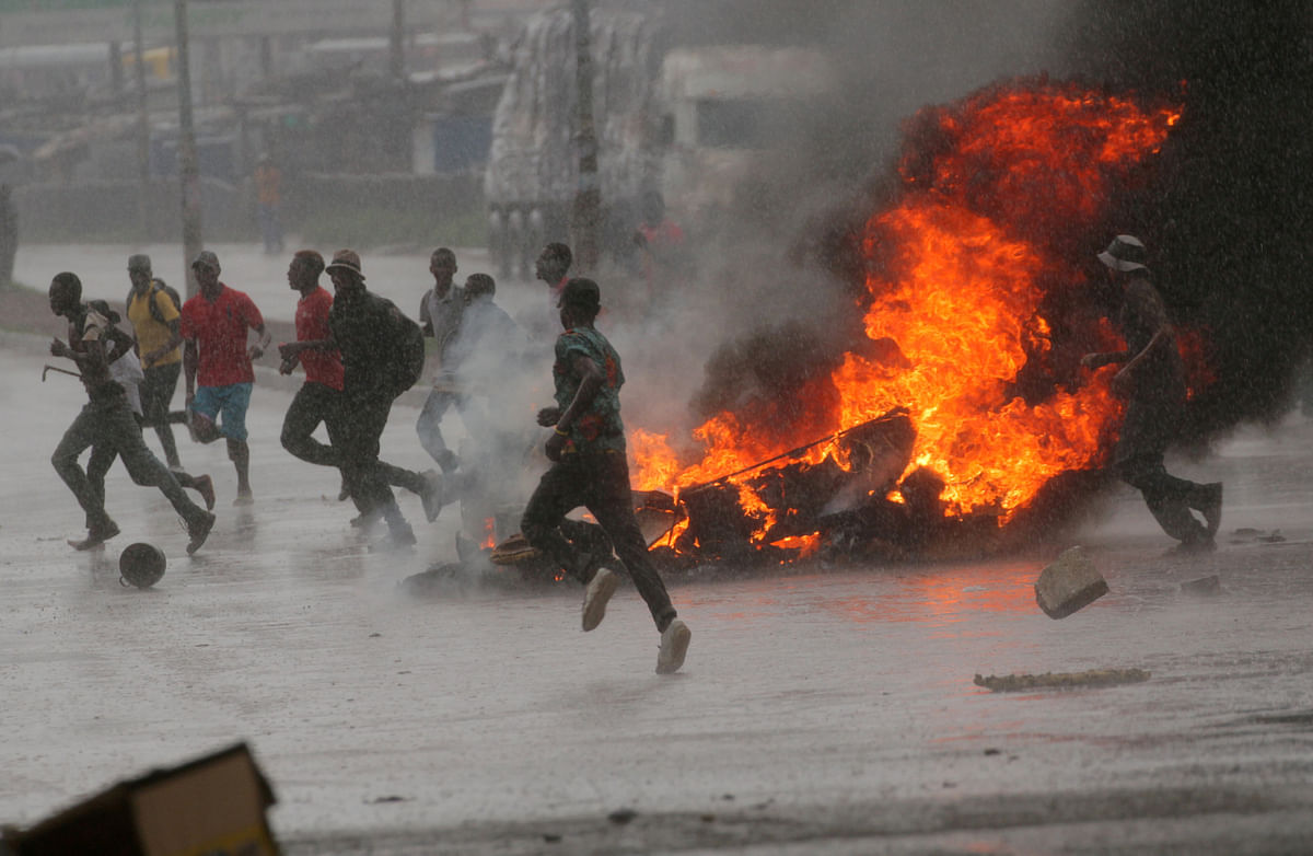 People run at a protest as barricades burn during rainfall in Harare, Zimbabwe on 14 January 2019. Photo: Reuters