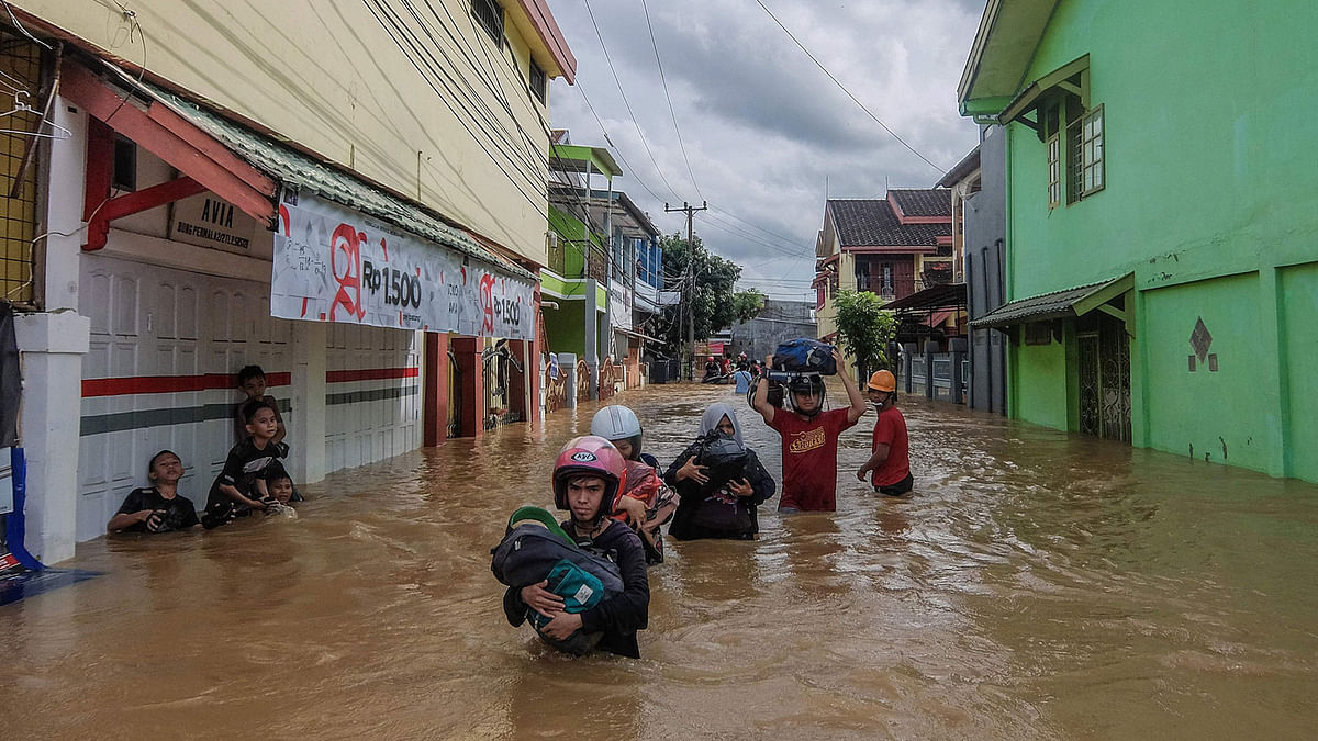 This picture taken on 23 January 2019 shows residents evacuating their homes in Makassar as heavy rain and strong winds pounded the southern part of Sulawesi island, swelling rivers that burst their banks and inundating dozens of communities in nine southern districts. Photo: AFP