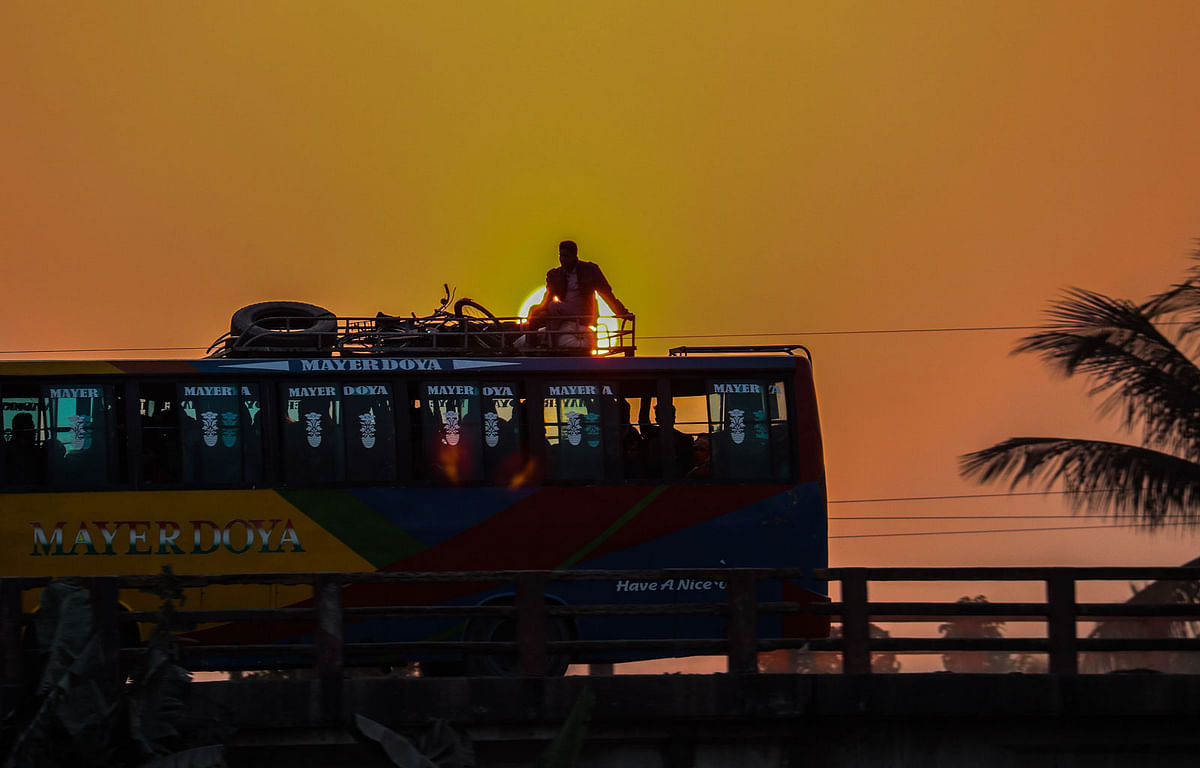 A passenger on top of a moving bus during twilight on Baliakhali Bridge in Dumuria, Khulna on 25 January. Photo: Saddam Hossain