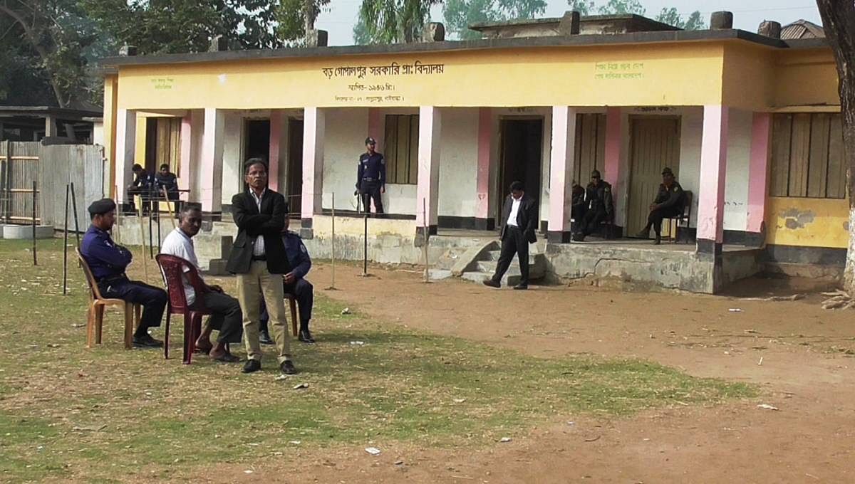 Elections officials and law enforcement members gossip as there are not voters at Boro Gopalpur Government Primary School centre on Sunday. Photo: UNB