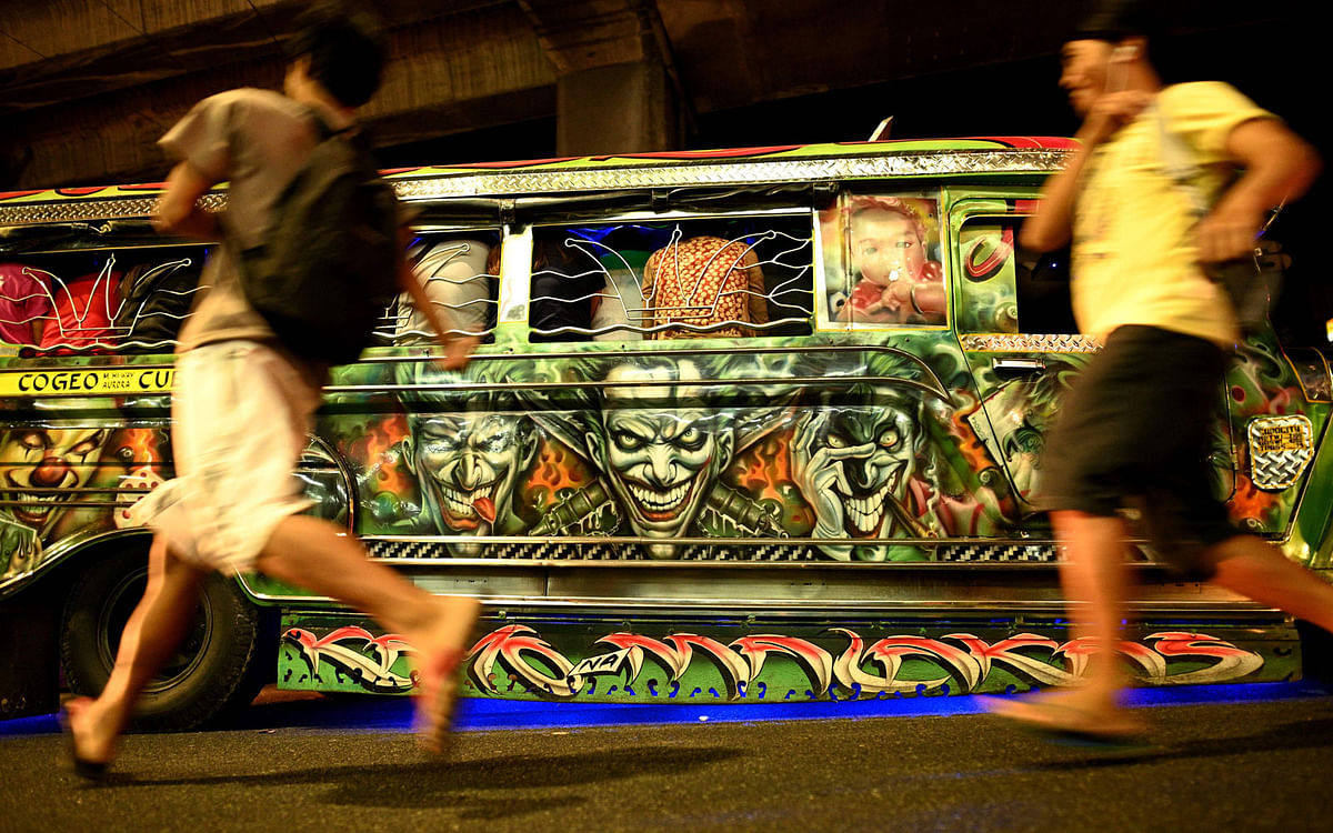 This picture taken on 14 January 2019 shows custom artwork on the side of a jeepney as commuters run to catch a ride on the vehicle during rush hour in Manila. Photo: AFP