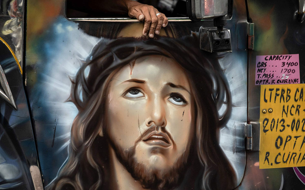 This picture taken on 13 January 2019 shows a depiction of Jesus Christ painted on the door of a jeepney during rush hour in Manila.   Hand-painting custom decor on jeepneys adorned with images of everything from Batman to babies, as well as disco lights and chrome wheels, has for decades provided cheap transport for millions. Photo: AFP
