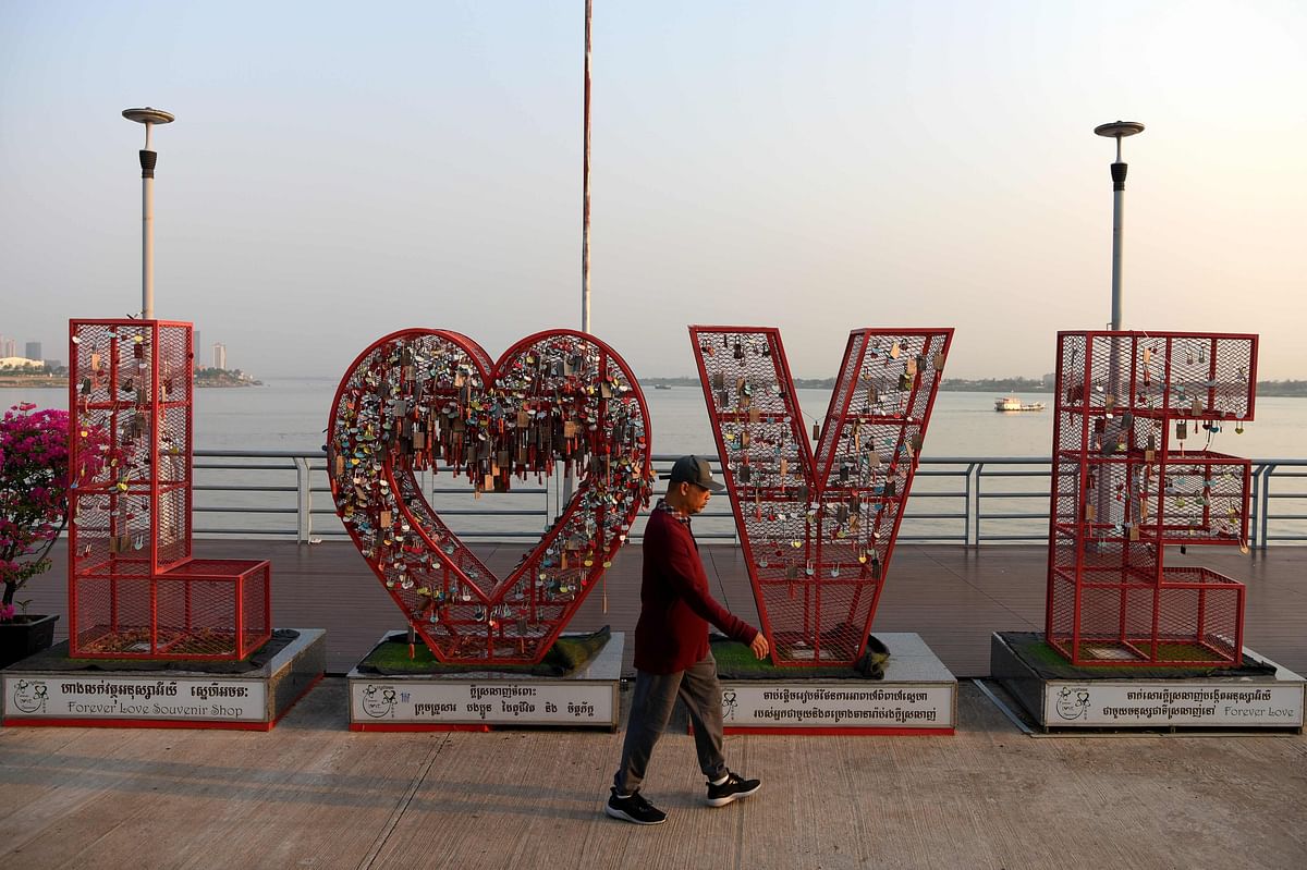 A man walks past `love` metal sign filled with locks left by couples along a river connecting to Mekong River in Phnom Penh on 29 January 2019. Photo: AFP