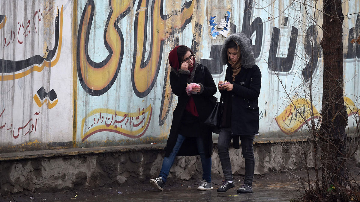 In this photo taken on 30 January, 2019, Afghan girls walk next to graffitis on a wall in Kabul. Afghan women are watching with trepidation as the US draws closer to a deal with the Taliban, with many defiant at the thought of losing any of the hard-won progress they have made in the deeply patriarchal country since the Islamists were toppled in 2001. Photo: AFP