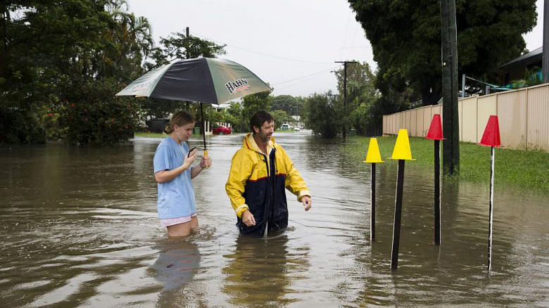 Resident Paul Shafer and his daughter Lily in flood waters near star pickets that show where the storm water cover has been removed in Hermit Park, Townsville, in northern Queensland on 2 February 2019. PHOTO: REUTERS