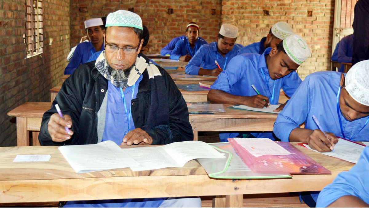 Shafiqul Islam writes his answer script in the Dakhil (vocational) examination in Bogura. Photo: UNB