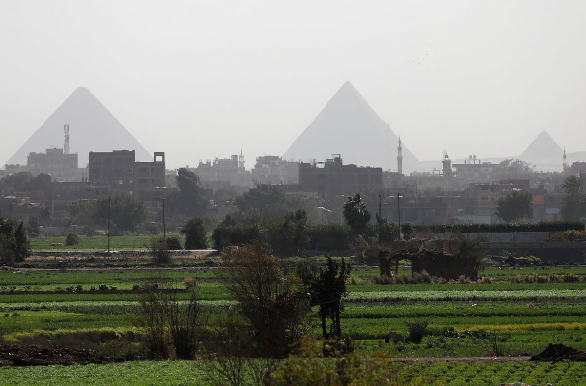 Houses and farmers working in the field are seen in front of the Great Pyramids at a highway leading to the capital city of Cairo. Photo: Reuters
