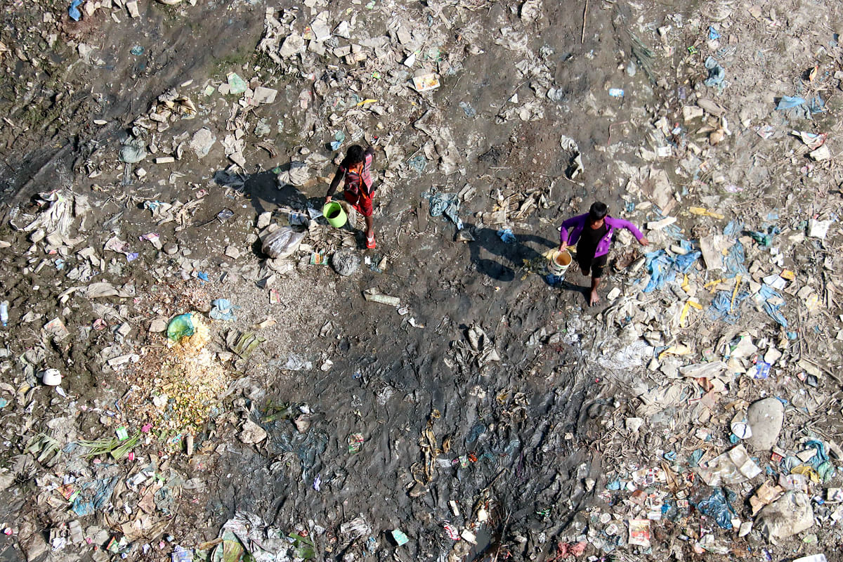 Two boys carrying water on the banks of river Surma amid garbage at Kabir Bazaar, Sylhet on 4 February. Photo: Anis Mahmud