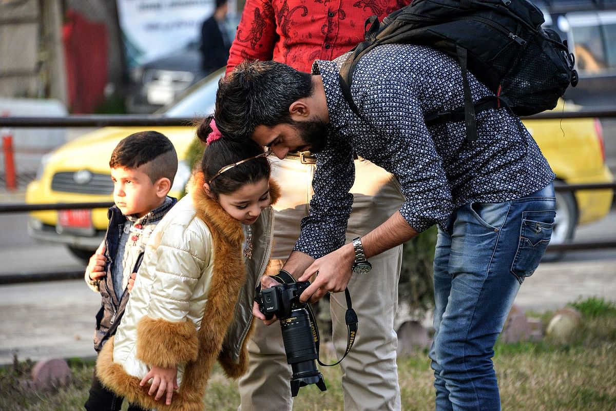 An Iraqi photographer shows a girl a picture taken on his camera at Nafoura square in the al-Zuhur neighbourhood in the eastern part of the northern Iraqi city of Mosul on 5 January. AFP File Photo