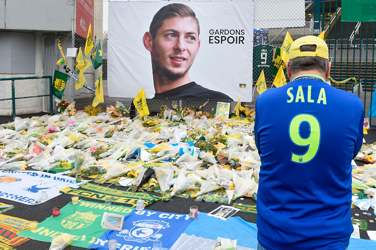 A supporter stands in front of flowers placed in front of a giant portrait of Argentinian former Nantes` forward Emilianio Sala outside La Beaujoire stadium before the French Cup football match between FC Nantes and Toulouse FC in Nantes on 5 February 2019. Photo: AFP