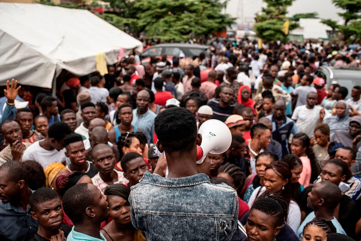 People gathering at one of the Permanent Voter Cards (PVCs) collection points in Lagos listen attentively for names to be called out over a megaphone to receive their voting card on 8 February 2019. Photo: AFP