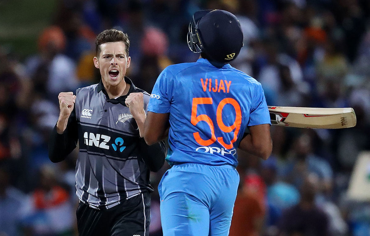 New Zealand`s Mitchell Santner (L) celebrates the wicket of India`s Vijay Shankar (R) during the third Twenty20 international cricket match between New Zealand and India in Hamilton on 10 February, 2019. Photo: AFP