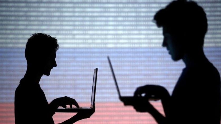 People are silhouetted as they pose with laptops in front of a screen projected with binary code and a Russian national flag, in this picture illustration taken in Zenica, Bosnia and Herzegovina on 29 October 2014. -- Photo: Reuters