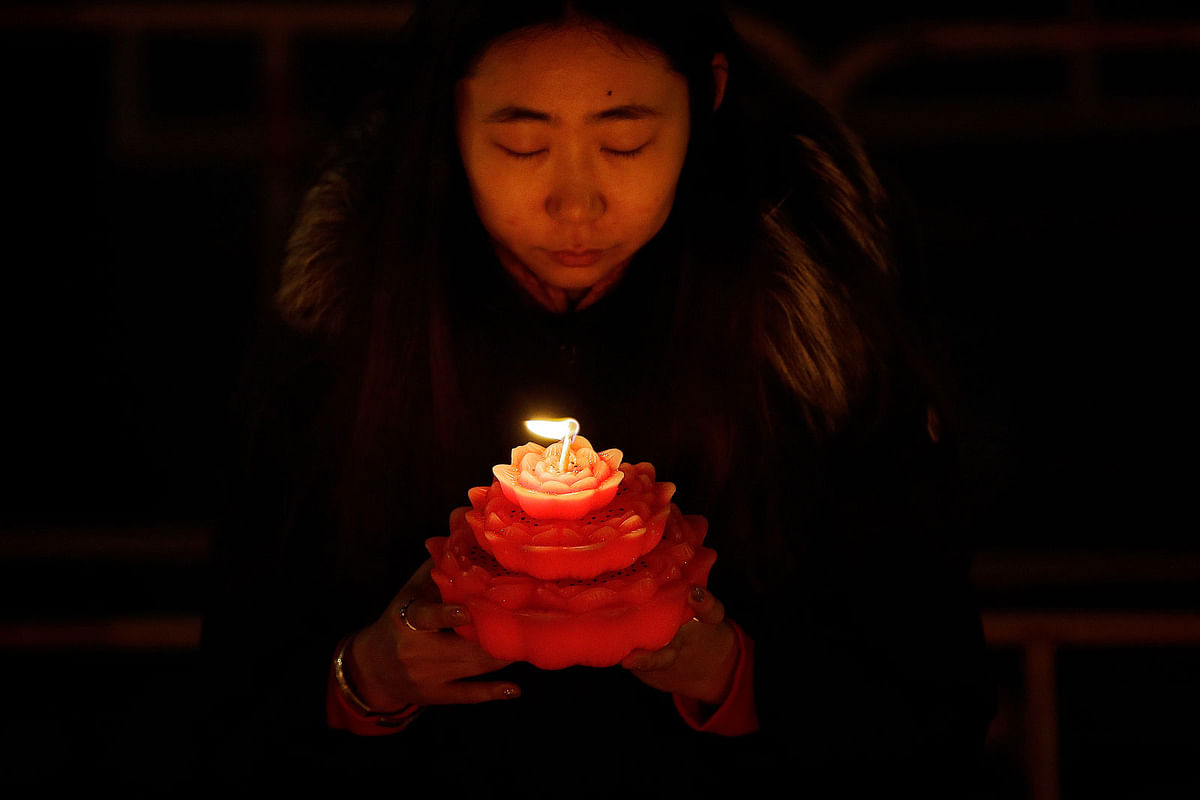 A woman holds a flower-shaped candle as she offers prayers on the first day of the Chinese Lunar New Year at the Tanzhe temple in the Mentougou District of Beijing, Tuesday, 5 February 2019. Photo: AP