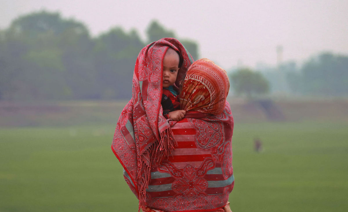 A woman covers her child with shawl as the weather turned cold on 18 February in Samaurakandi in Sylhet. Photo: Anis Mahmud