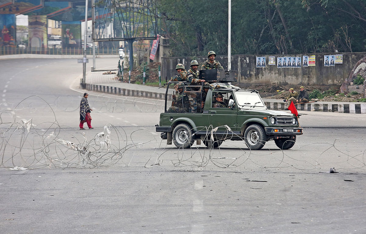 Indian army soldiers in a vehicle patrol a street as a woman walks past during a curfew in Jammu, 17 February, 2019. Photo: Reuters