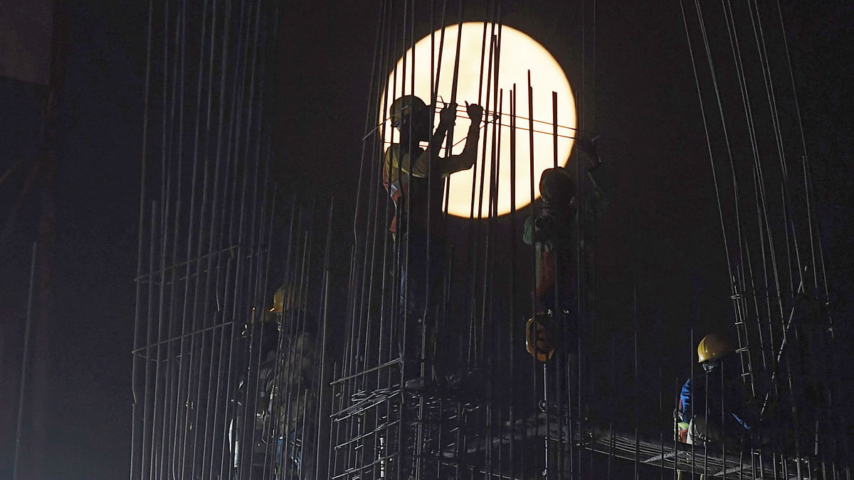 A `Super Snow Moon` rises as Indian construction labourers work at a building site in Kolkata on 19 February 2019. Super Moon is a term used when a full moon is at or near its closest approach to Earth. Photo: AFP