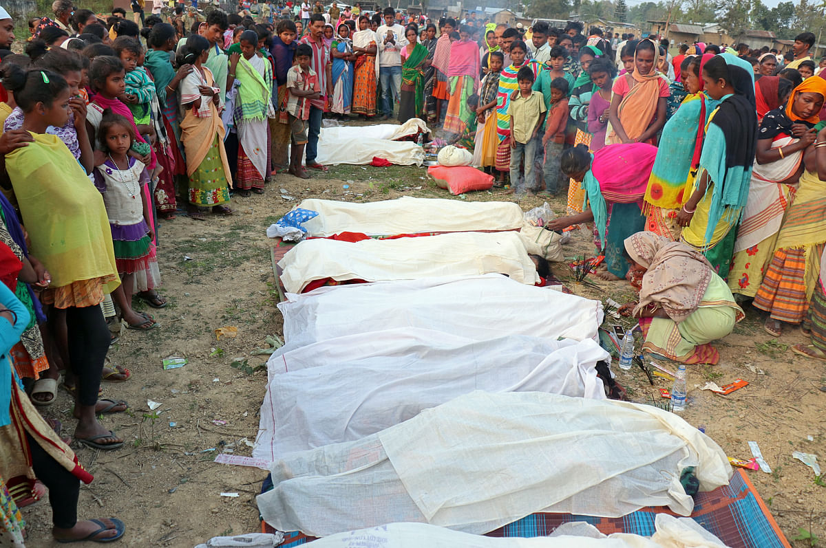 People stand next to the bodies of tea plantation workers, who died after consuming bootleg liquor, in Golaghat in the northeastern state of Assam, India, on 22 February 2019. Photo: Reuters