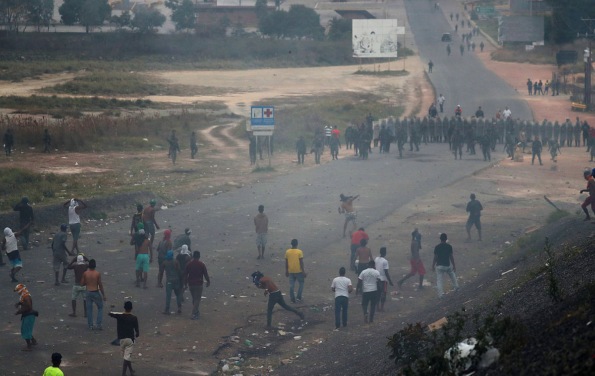 Venezuelan demonstrators throw stones during clashes with authorities, at the border between Brazil and Venezuela, Saturday, 23 February 2019. Photo: AP