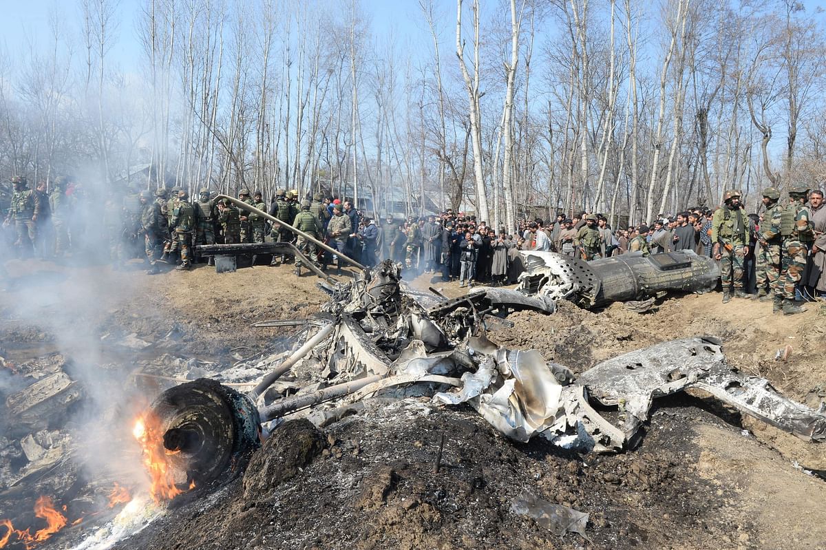 Indian soldiers and Kashmiri onlookers stand near the remains of an Indian Air Force (IAF) fighter jet after it crashed in Budgam district, some 30 kms from Srinagar on 27 February 2019. Photo: AFP