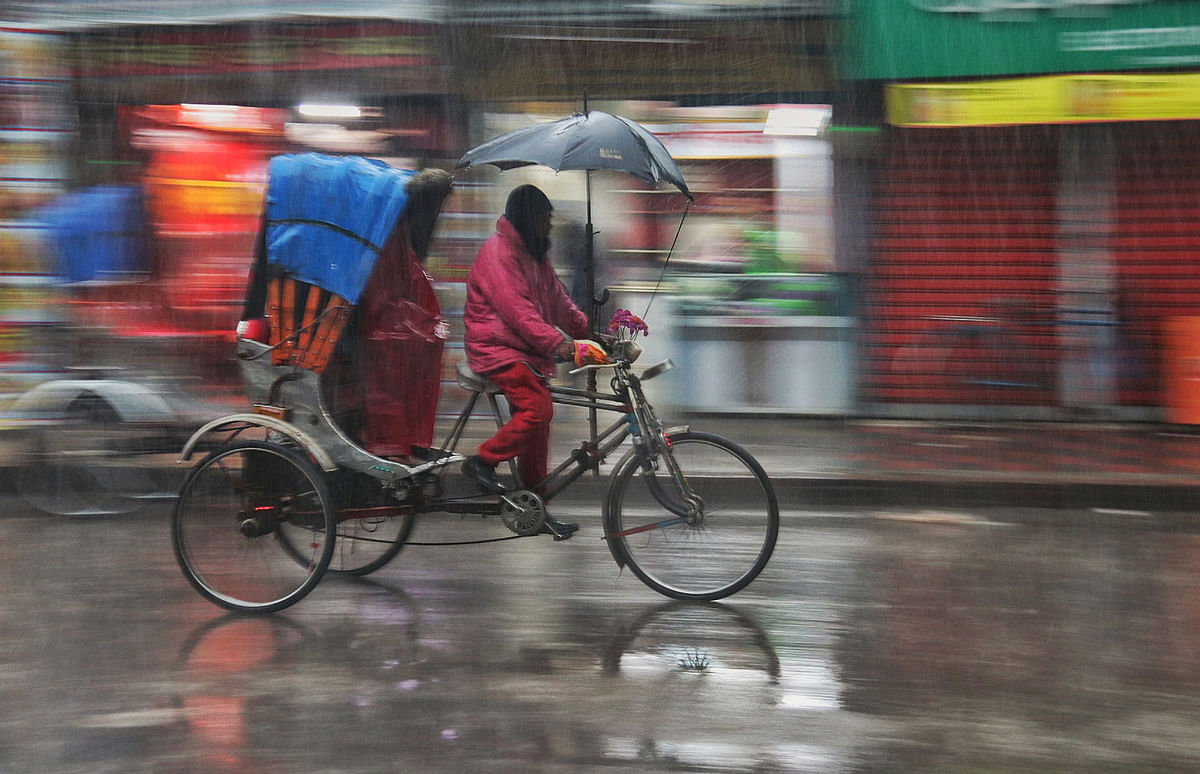 A rickshaw puller rushing with his vehicle in the rain at Picture Palace intersection in Khulna on 26 February. People across the country suffer due to the two-day rain caused by a depression. Photo: Saddam Hossain