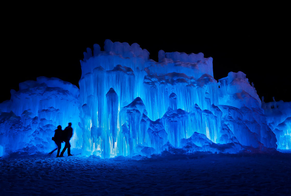 In this 26 January 2019 photo, a couple heads towards an entrance to a cavern at Ice Castles in North Woodstock, NH A team starts building massive walls in December to create a spectacular winter experience. Photo: AP