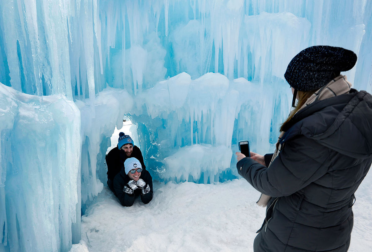 In this 26 January 2019 photo, visitors pose for a photo in a tunnel at Ice Castles in North Woodstock, NH. With a seemingly endless variety of photo-ops, most visitors have a hard time putting their cameras down. Photo: AP