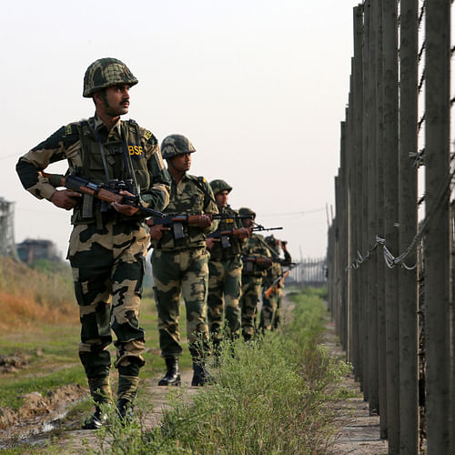 India's Border Security Force soldiers patrol along the fenced border