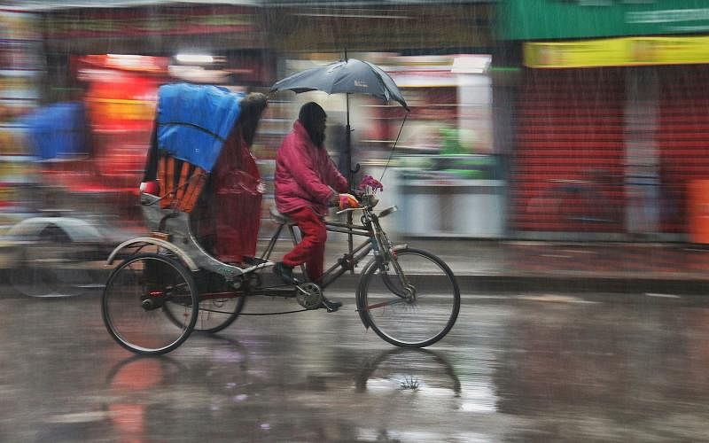 A rickshaw puller rushing with his vehicle in the rain at Picture Palace intersection in Khulna on 26 February. People across the country suffer due to the rain caused by a depression. Photo: Saddam Hossain