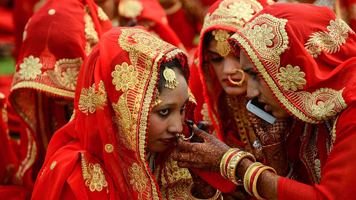 An Indian Muslim bride-to-be arranges the jewellery of another one as they participate in a mass wedding ceremony in Ahmedabad on 3 March.  Photo: AFP