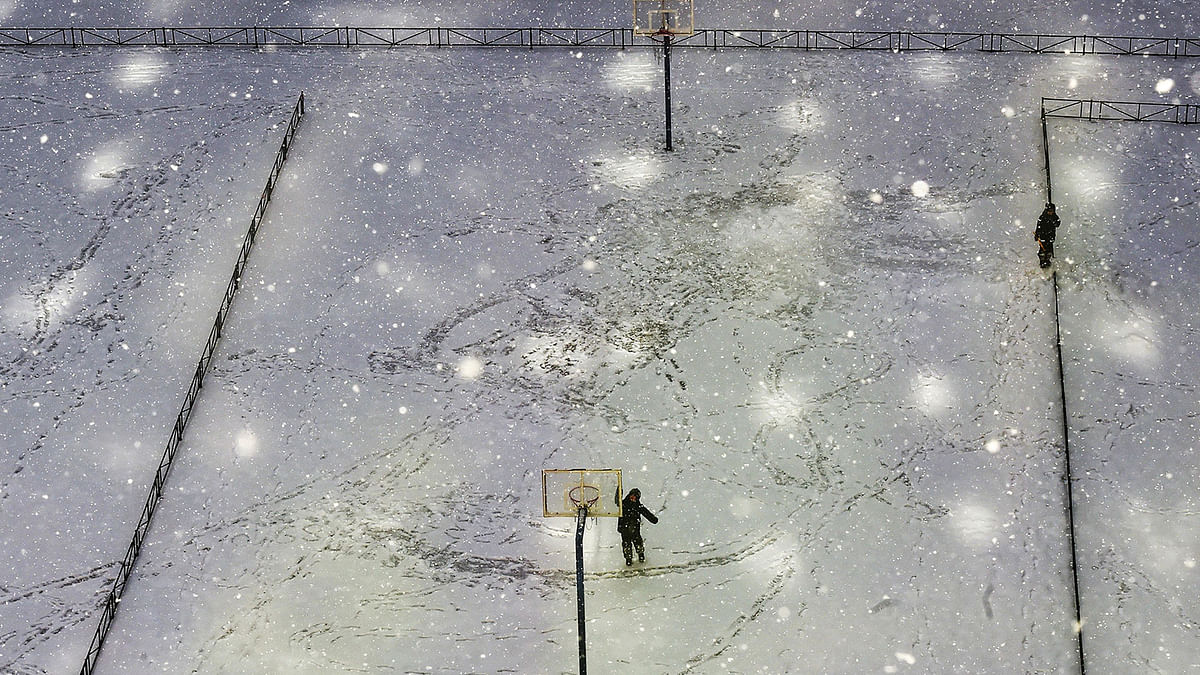 Boys play on a sports ground during a snowfall under the rays of the sun in Saint Petersburg on 3 March 2019. Photo: AFP