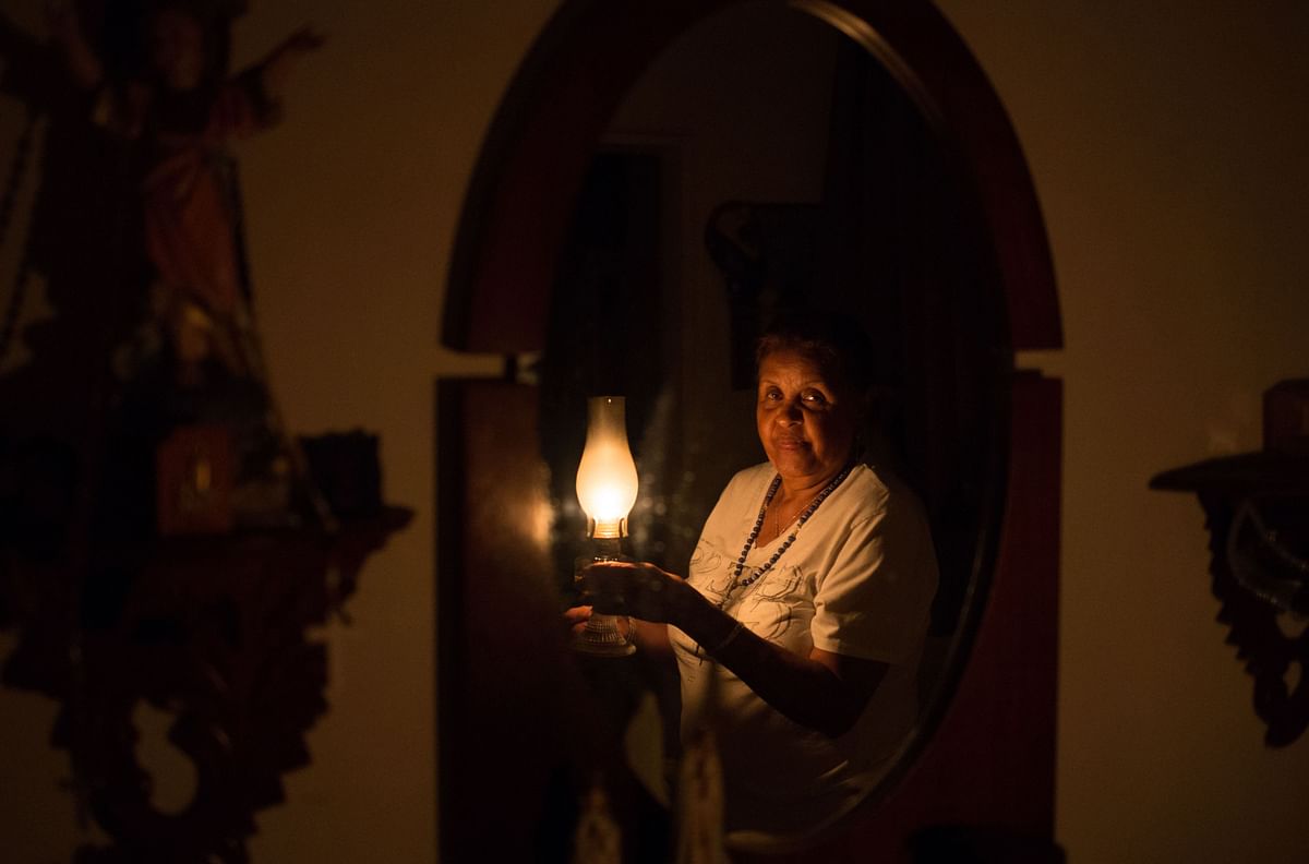Venezuelan Elvia Helena Lozano is reflected on a mirror as she uses a kerosene lamp during a power outage at her home in Caracas on 9 March 2019. Photo: AFP