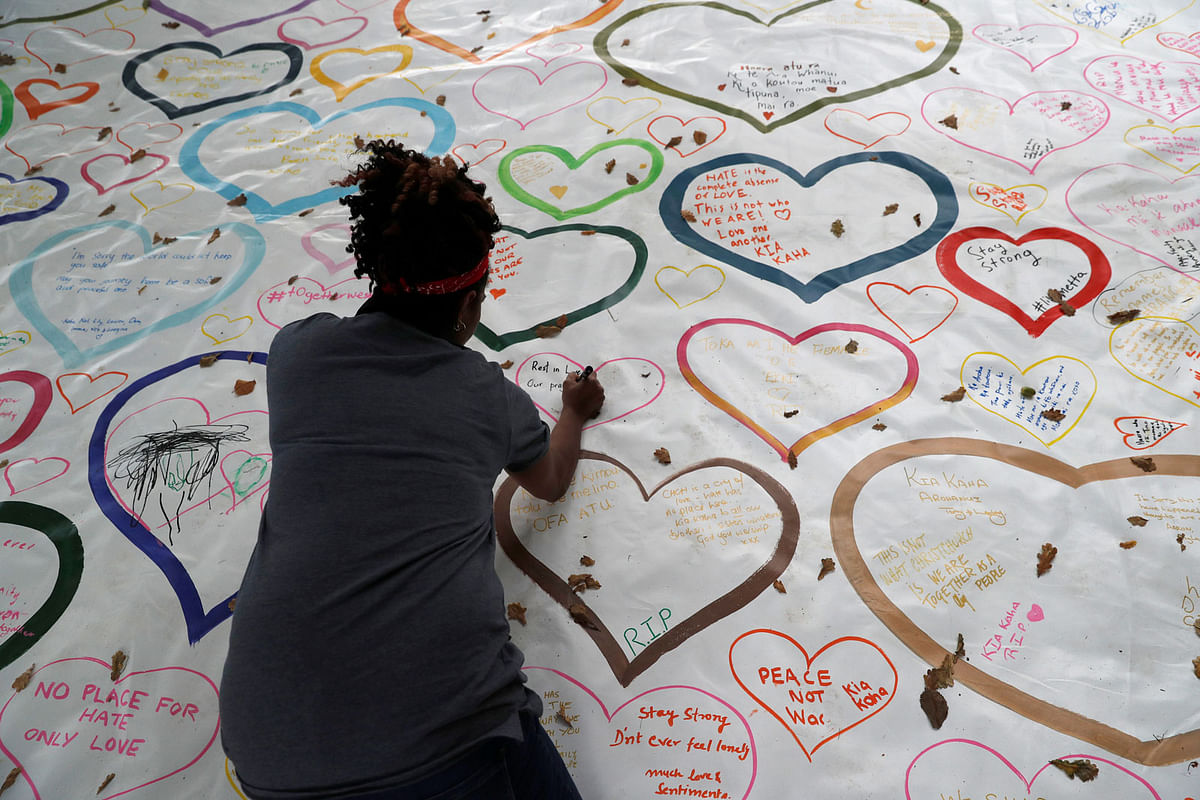 People write on a sign at a memorial as a tribute to victims of the mosque attacks, near a police line outside Masjid Al Noor in Christchurch, New Zealand, on 16 March 2019. Photo: Reuters