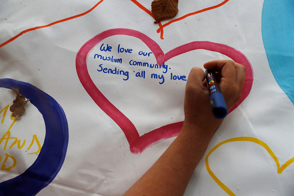 People write on a sign at a memorial as a tribute to victims of the mosque attacks, near a police line outside Masjid Al Noor in Christchurch, New Zealand, on 16 March 2019. Photo: Reuters