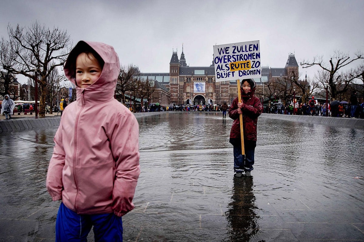 A girl holds a placard reading `We will be flooded if [Netherlands` prime minister Mark] Rutte keeps on dreaming` during a march in support of the climate, on 10 March in Amsterdam, asking for climate action by politics and corporates. Photo: AFP