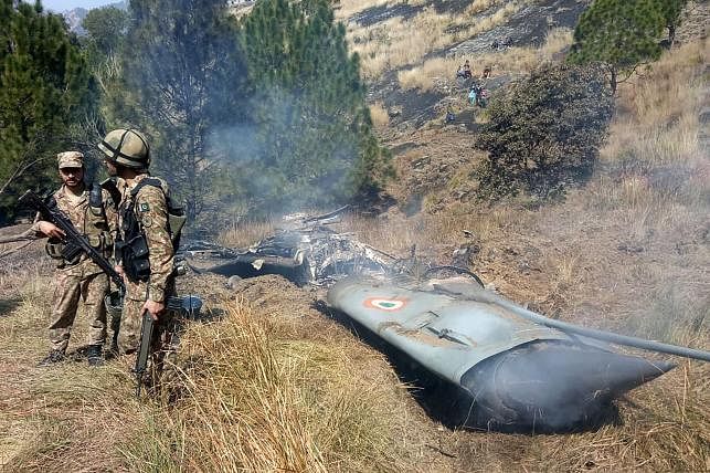 Pakistani soldiers stand next to what Pakistan says is the wreckage of a shot down Indian fighter jet in Pakistan-controlled Kashmir. Photo: AFP