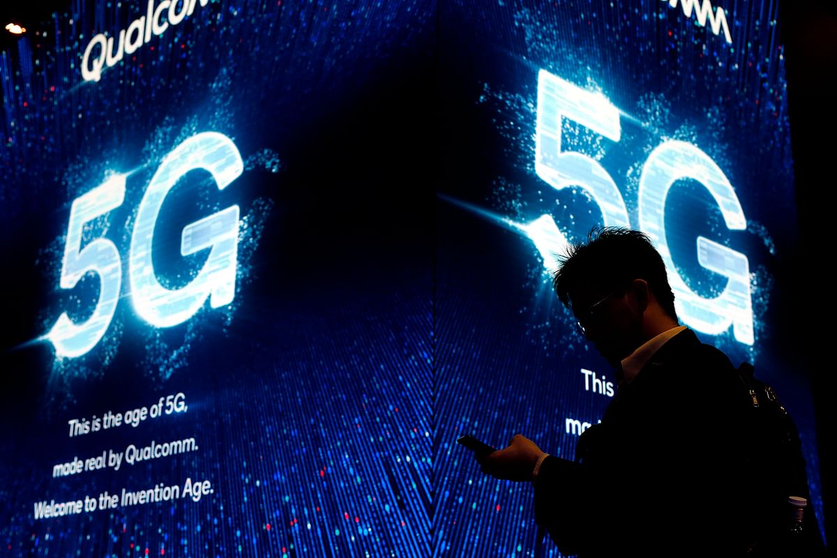 In this file photo taken on 27 February a man uses his phone next to a 5G sign at the Qualcomm stand at the Mobile World Congress (MWC) in Barcelona. Photo: AFP