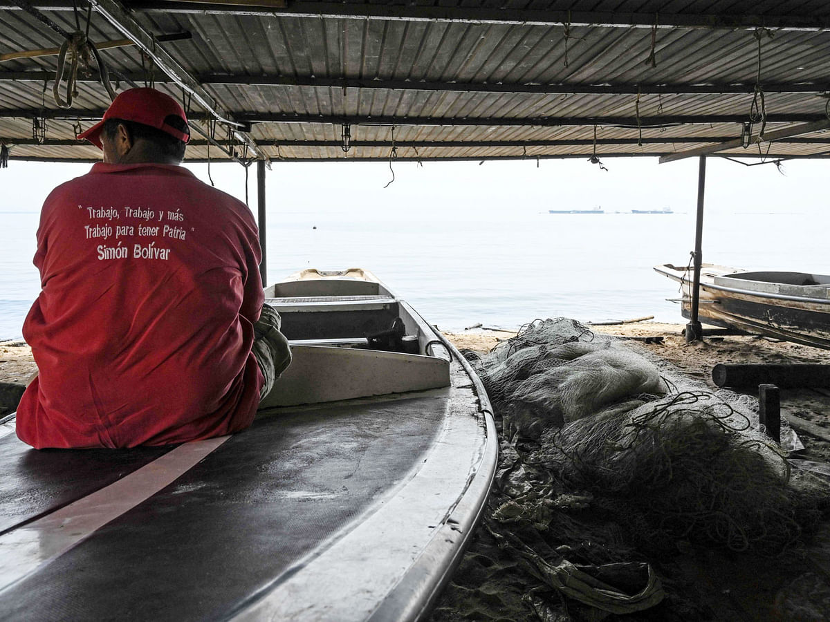 In this file picture taken on March 15, 2019 a fisherman sits on a boat by Lake Maracaibo in the Venezuelan city of Maracaibo. Venezuela is in the grip of a humanitarian crisis due to shortages of food and medicine exacerbated by hyperinflation. People are turning to fishing and hunting to take some food home. AFP