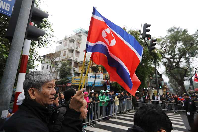 People wave flags near security personnel as they wait for the motorcade of North Korean leader Kim Jong Un outside the Melia hotel ahead of the North Korea-US summit in Hanoi, Vietnam on 26 February. Photo: Reuters