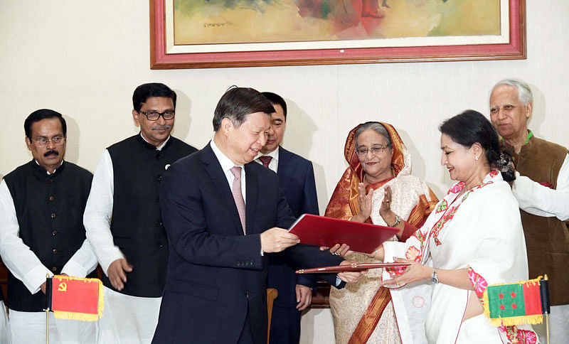 Bangladesh Awami League international affairs secretary Shammi Ahmed and Song Tao handing over the MoU copies on behalf of their respective parties in presence of prime minister Sheikh Hasina at Ganabhaban, Dhaka. Photo: PID