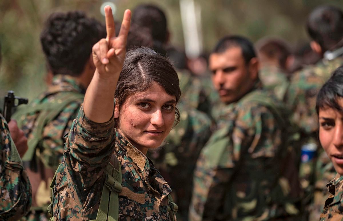 A female fighter of the US-backed Kurdish-led Syrian Democratic Forces (SDF) flashes the victory gesture while celebrating near the Omar oil field in the eastern Syrian Deir Ezzor province on 23 March, 2019, after announcing the total elimination of the Islamic State (IS) group's last bastion in eastern Syria. Photo: AFP