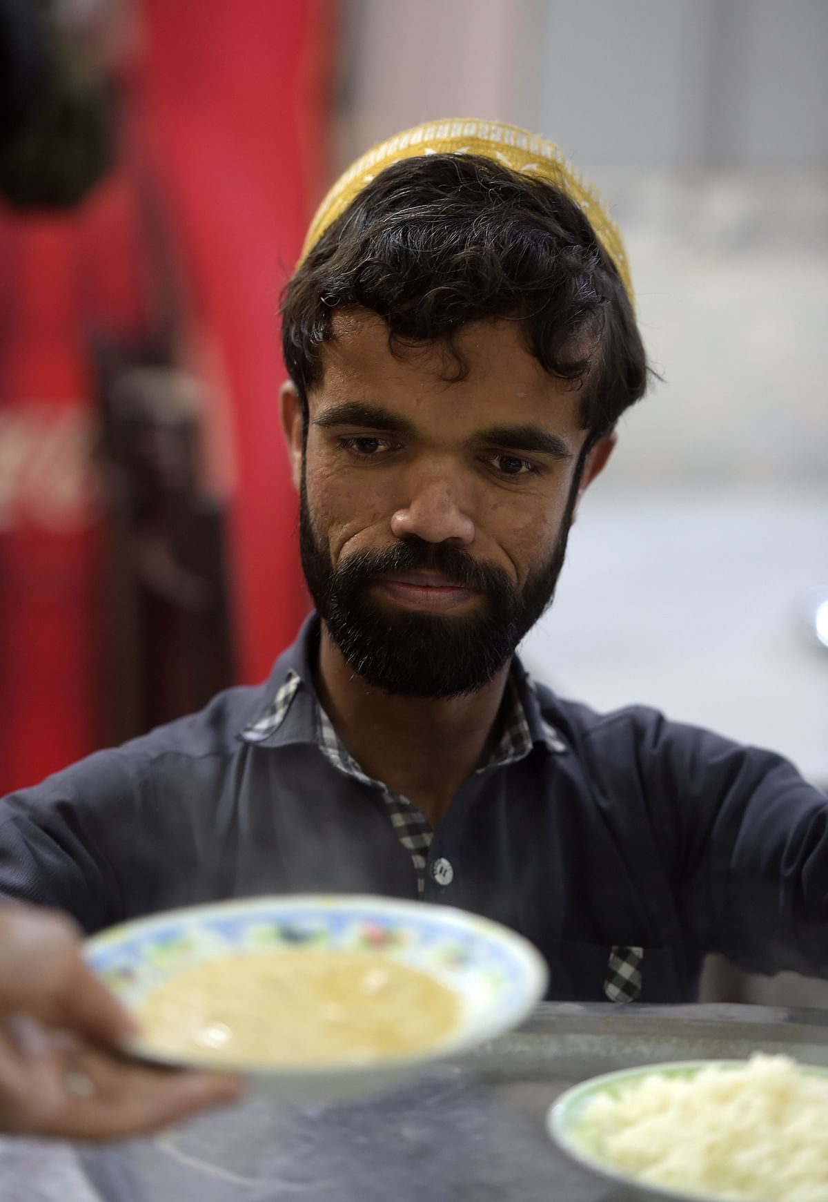 In this picture taken on 22 February 2019, Rozi Khan, a 25-year-old Pakistani waiter who resembles US actor Peter Dinklage, prepares to serve food to customers at Dilbar Hotel in Rawalpindi. Photo: AFP