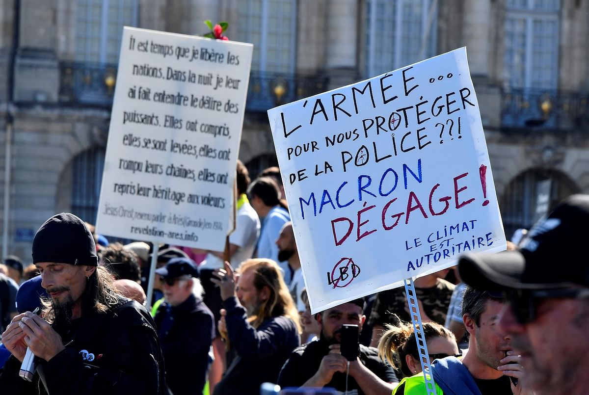 A protester holds a placard, reading `The army... To protect us from the police ??! Macron get out !` during an anti-government demonstration called by the `Yellow Vest` (gilets jaunes) movement, in a street in Bordeaux, southwestern France, on March 23, 2019. Demonstrators hit French city streets again on March 23, for a 19th consecutive week of nationwide protest against the French President`s policies and his top-down style of governing, high cost of living, government tax reforms and for more `social and economic justice.` AFP