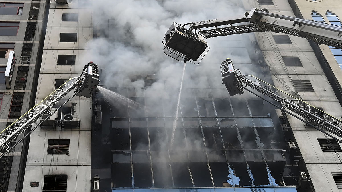 Firefighters on ladders work to extinguish a blaze in an office building in Dhaka on 28 March 2019. Photo: AFP