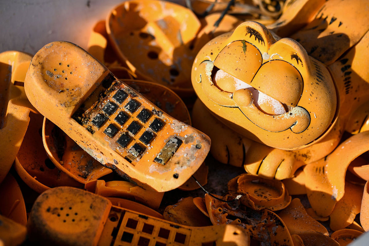 Spare parts of plastic `Garfield` phones are displayed on the beach on 28 March in Plouarzel, western France, after being collected from a sea cave by environmental activists. Photo: AFP